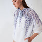 The Tea Garden Lantern Blouse from Norah Boutique features a relaxed fit with lantern sleeves and a delicate floral print, reminiscent of a serene garden. The ivory and lavender colors add a touch of femininity, making it perfect for any occasion, whether dressed up or down. The lightweight material provides comfort and breathability, ideal for warmer weather. Add a touch of elegance to your wardrobe with the Tea Garden Lantern Blouse.